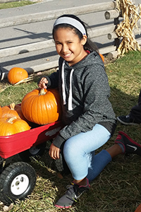 photo of Taimane, sitting beside a wagon with a pumpkin